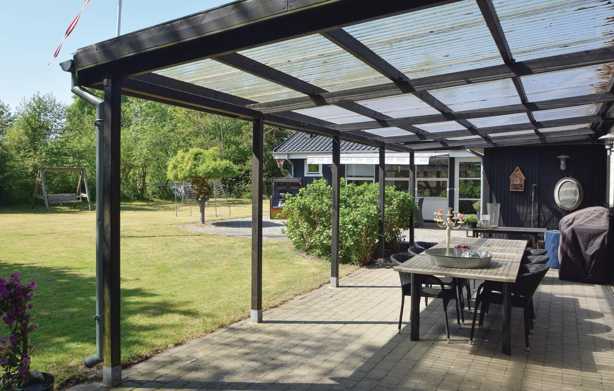 Ein überdachter Patio-Bereich mit Tisch, Stühlen, Grill und einem Basketballkorb.