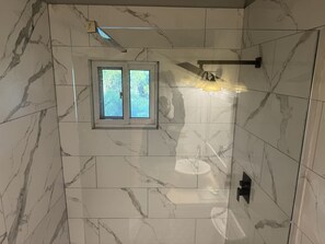 Een bad/douchecombinatie, handdoeken, zeep, toiletpapier