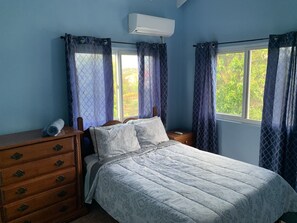 Ein Schlafzimmer mit einem Bett, einem Holzschrank und einer Klimaanlage.