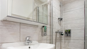 A modern bathroom with a white sink, a glass shower enclosure, and a mirrored cabinet. - The Broadway Hotel - London Heathrow (Southall)