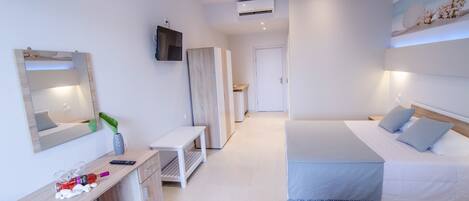 A modern bedroom with a large bed, bedside tables, a TV mounted on the wall, and an air conditioning unit.