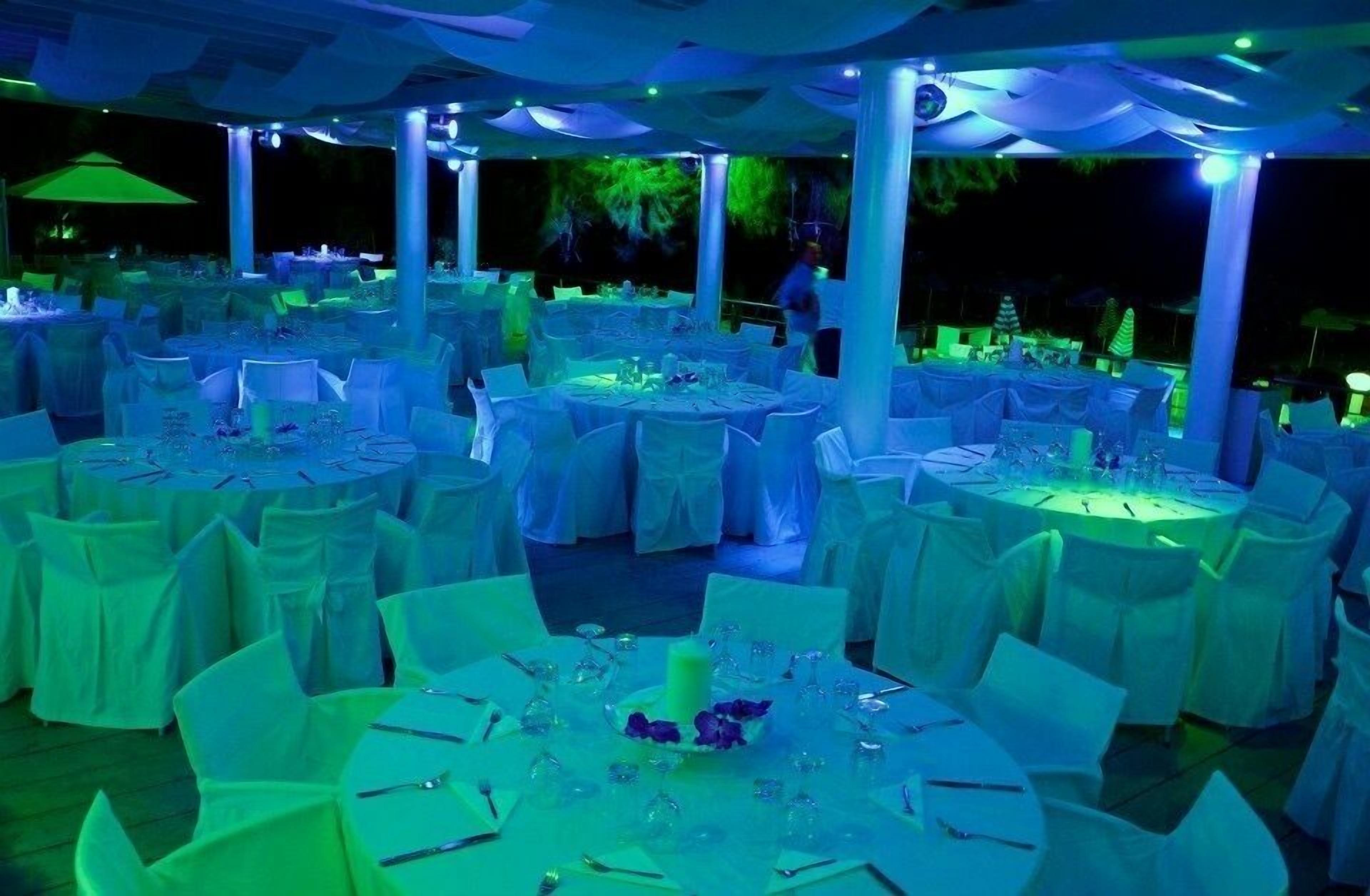 Een evenementenlocatie buiten met ronde tafels met witte tafellakens, gerangschikt in een cirkelvormig patroon.