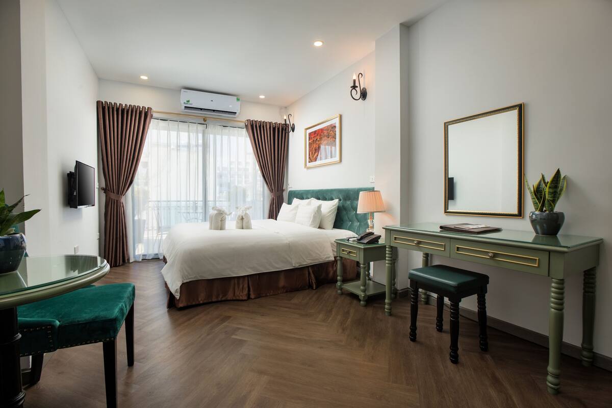 Ein Hotelzimmer mit Bett, Schreibtisch, Stuhl, Lampe und einer Zimmerpflanze.