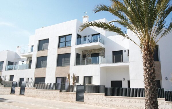 A modern multi-story building with balconies, a stone facade, and a palm tree in the foreground. - Amazing apartment in Arenales del sol (Arenales del sol)