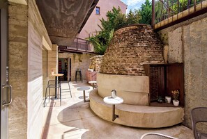 A courtyard with a stone wall, outdoor seating, and a small garden area. - Hotel Melibea by gaiarooms (Salamanca)