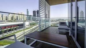 Un balcón moderno con vistas a un paisaje urbano, incluyendo rascacielos y una autopista.