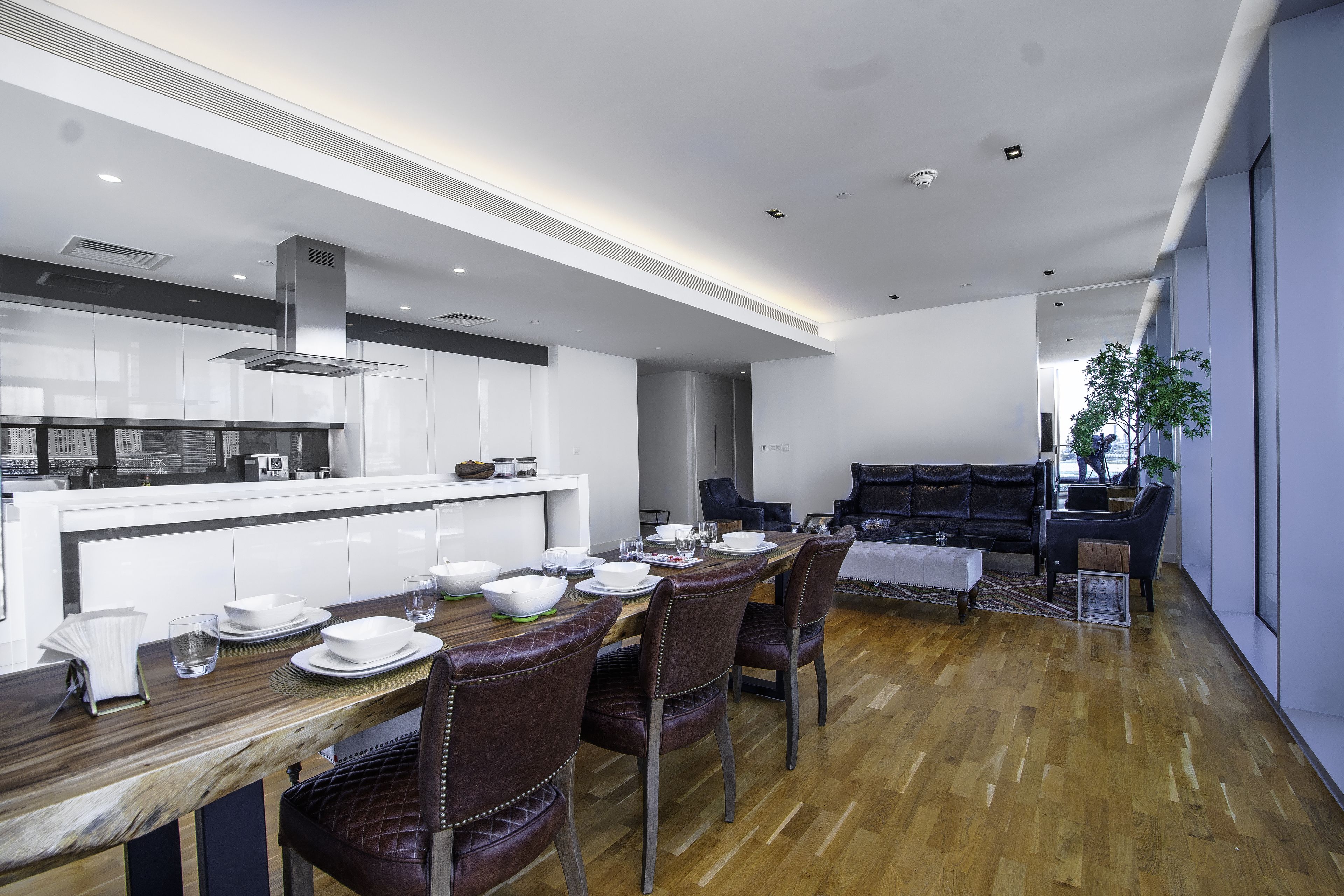 Eine moderne Küche mit weißen Schränken und einem Essbereich mit einem Holztisch und Ledersesseln.