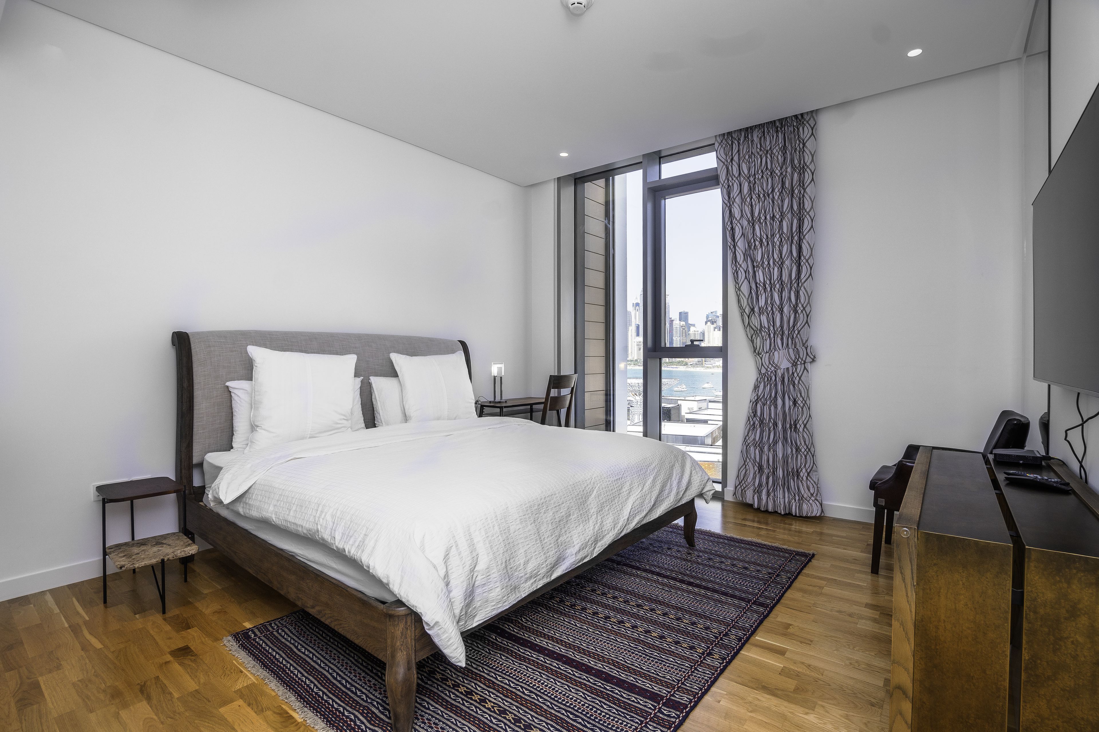 Une chambre d’hôtel moderne dotée d’un grand lit, d’un bureau et offrant une vue sur la ville grâce à une grande fenêtre.