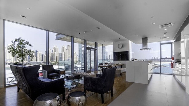 Una sala de estar moderna con vistas a la ciudad, ventanas amplias y muebles contemporáneos.