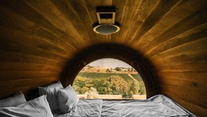 Un dormitorio con techo de madera y un amplio ventanal de arco.