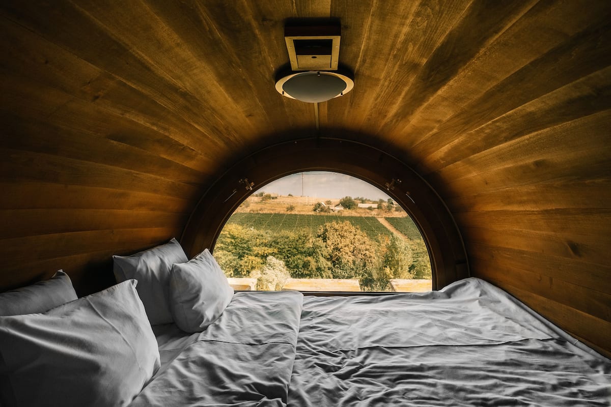 A bedroom with a wooden ceiling and a large arched window.