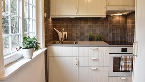 A kitchen with white cabinets, a stainless steel sink, a stove, and a window with plants on the windowsill. - 2 bedroom gorgeous home in Höllviken (Höllviken)