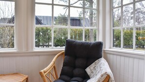 A room with a large window, a wicker chair, and a dark cushioned chair with a blanket. - 2 bedroom gorgeous home in Höllviken (Höllviken)