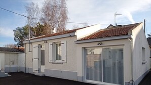 A single-story building with a tiled roof, a large sliding glass door, and a small window with shutters. - Holiday house near sea and shops (La Baule)