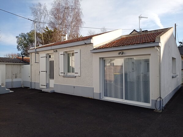A single-story building with a tiled roof, a large sliding glass door, and a small window with shutters. - Holiday house near sea and shops (La Baule)