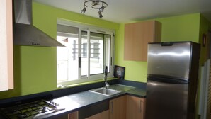 A kitchen with a gas stove, stainless steel refrigerator, and a window with blinds. - Holiday house near sea and shops (La Baule)