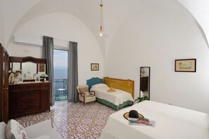 Ein Hotelzimmer mit Bett, Schminktisch, Stuhl, Balkon mit Blick und einem großen Spiegel.