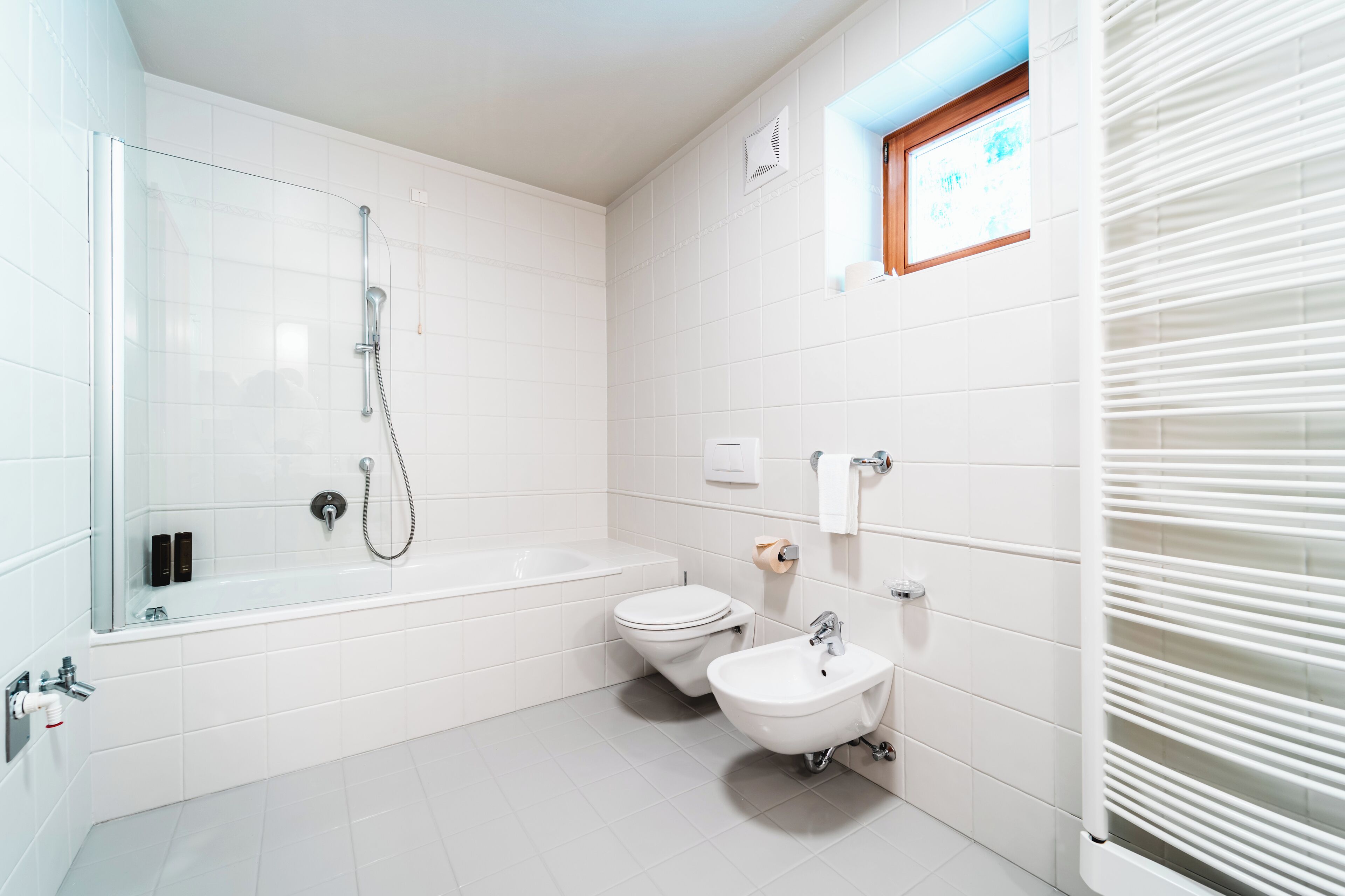 Un baño moderno con ducha envuelta en vidrio, una bañera, un inodoro y un bidé.