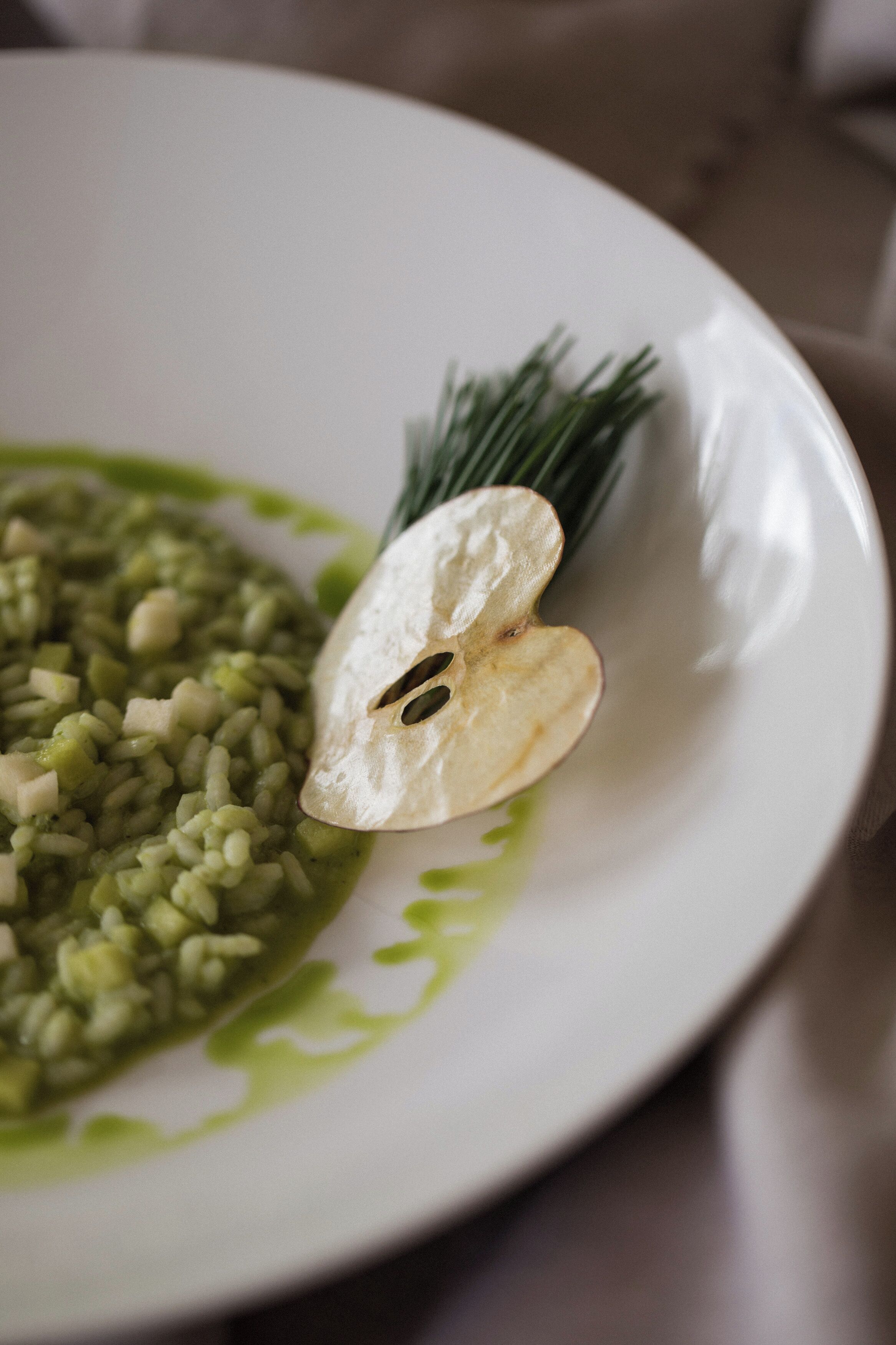 Un plato de comida con salsa verde y una porción de patata.