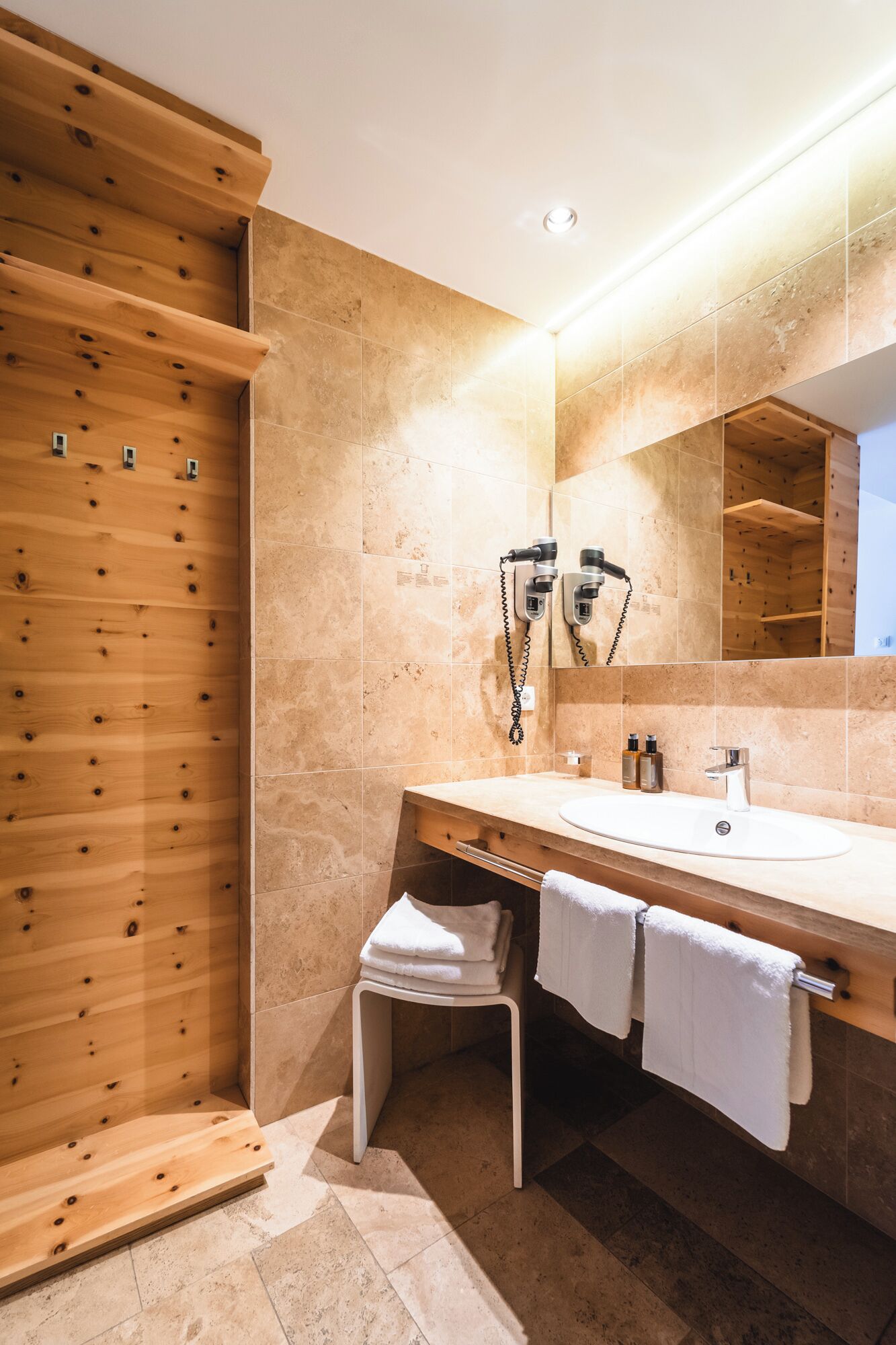 Un baño moderno con cabina de ducha de madera, un espejo grande y tocador con lavabo y toallero.