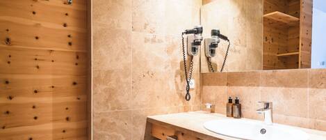 Un baño moderno con cabina de ducha de madera, un espejo grande y tocador con lavabo y toallero.