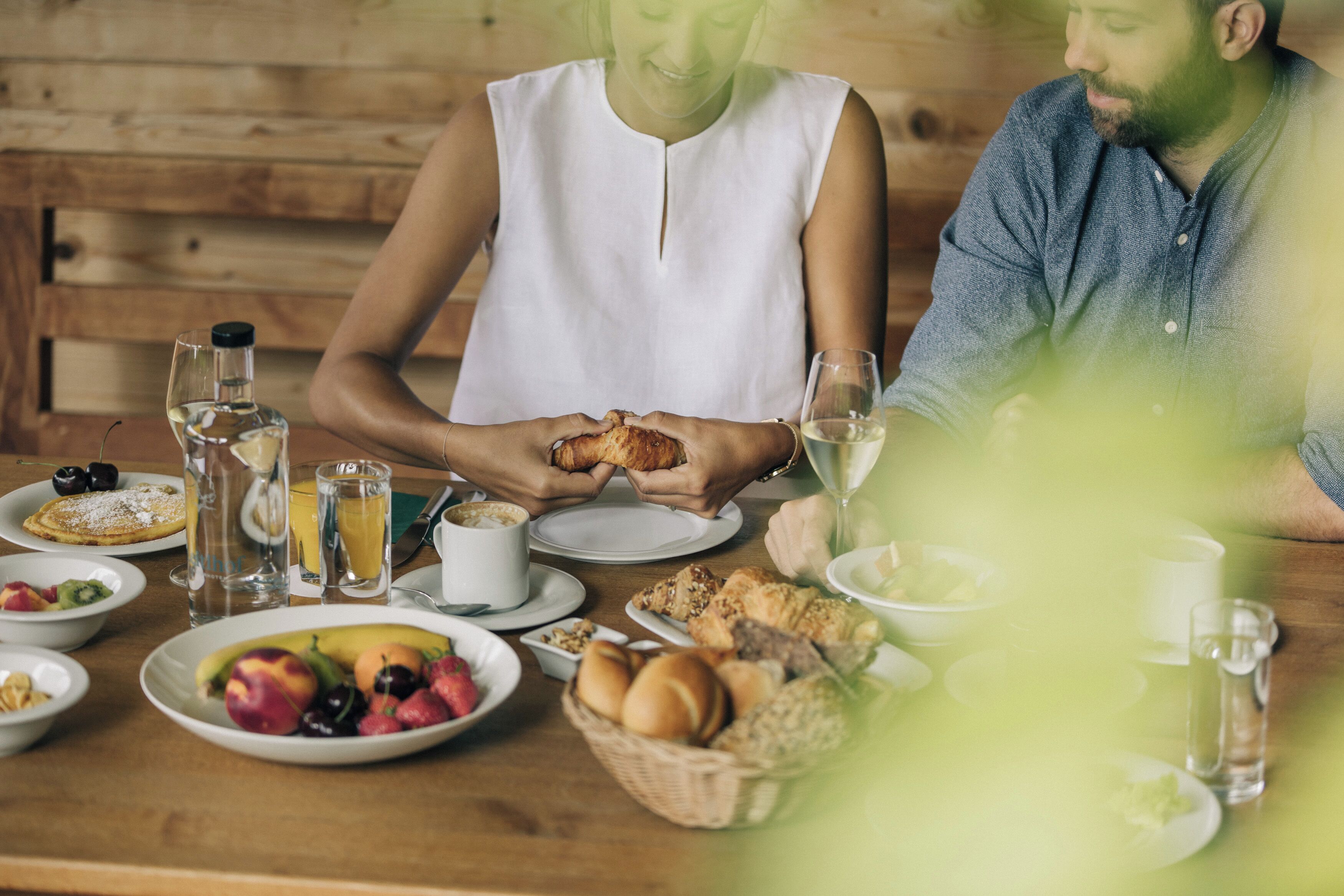 A breakfast setting with a wooden table, plates of food, and glasses of water and juice.