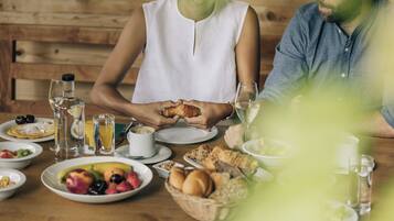 Una escena de desayuno con una mesa de madera, platos de comida y vasos de agua y jugo.