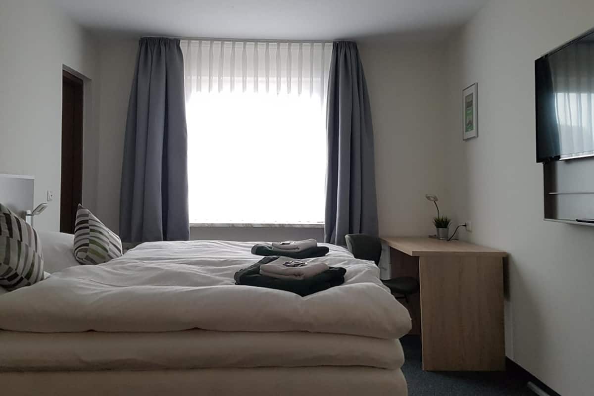 A hotel room with a bed, a desk, and a TV.