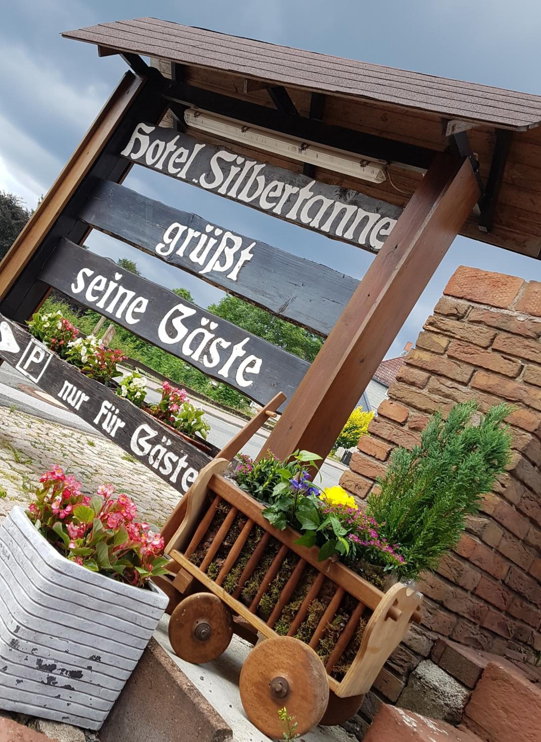 Un letrero de madera con el texto "Hotel Silberkammer" y "grüβt seine Gäste", indicando un mensaje de bienvenida a los huéspedes.