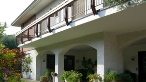 A building with a covered outdoor area featuring columns, potted plants, and a balcony with a railing. - Bed & Breakfast Villa Filotea (Desenzano del Garda)