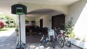 A covered outdoor area with a basketball hoop, a dining table, chairs, and bicycles. - Bed & Breakfast Villa Filotea (Desenzano del Garda)