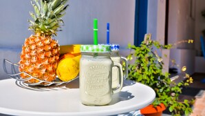 Una mesa con una piña, un vaso de una bebida cremosa y un limón.