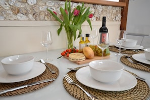 Una mesa dispuesta para una comida con cuencos blancos, cubiertos y una botella de vino.