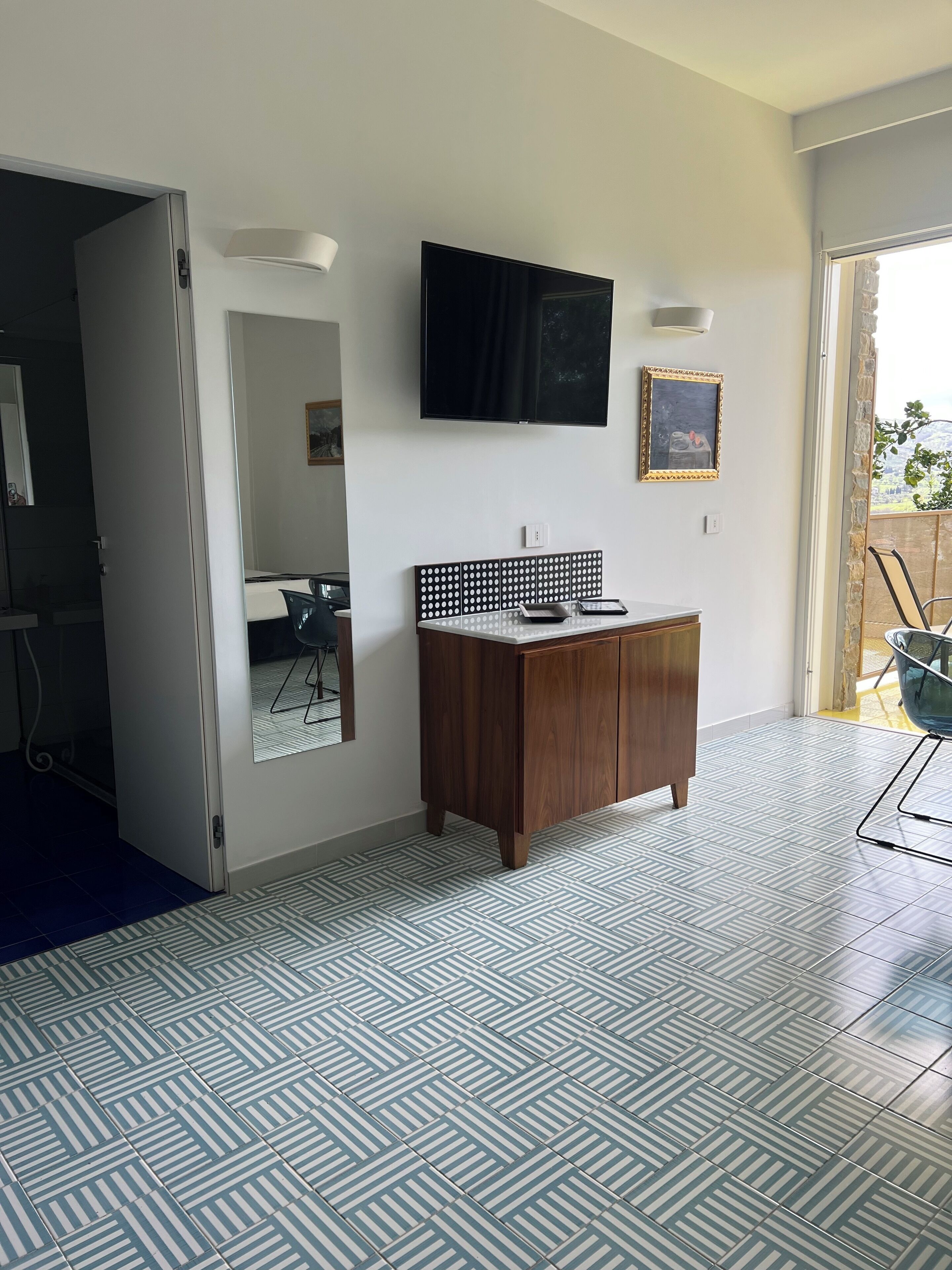 Uma sala de estar moderna com uma televisão grande, um armário de madeira e um chão estampado.