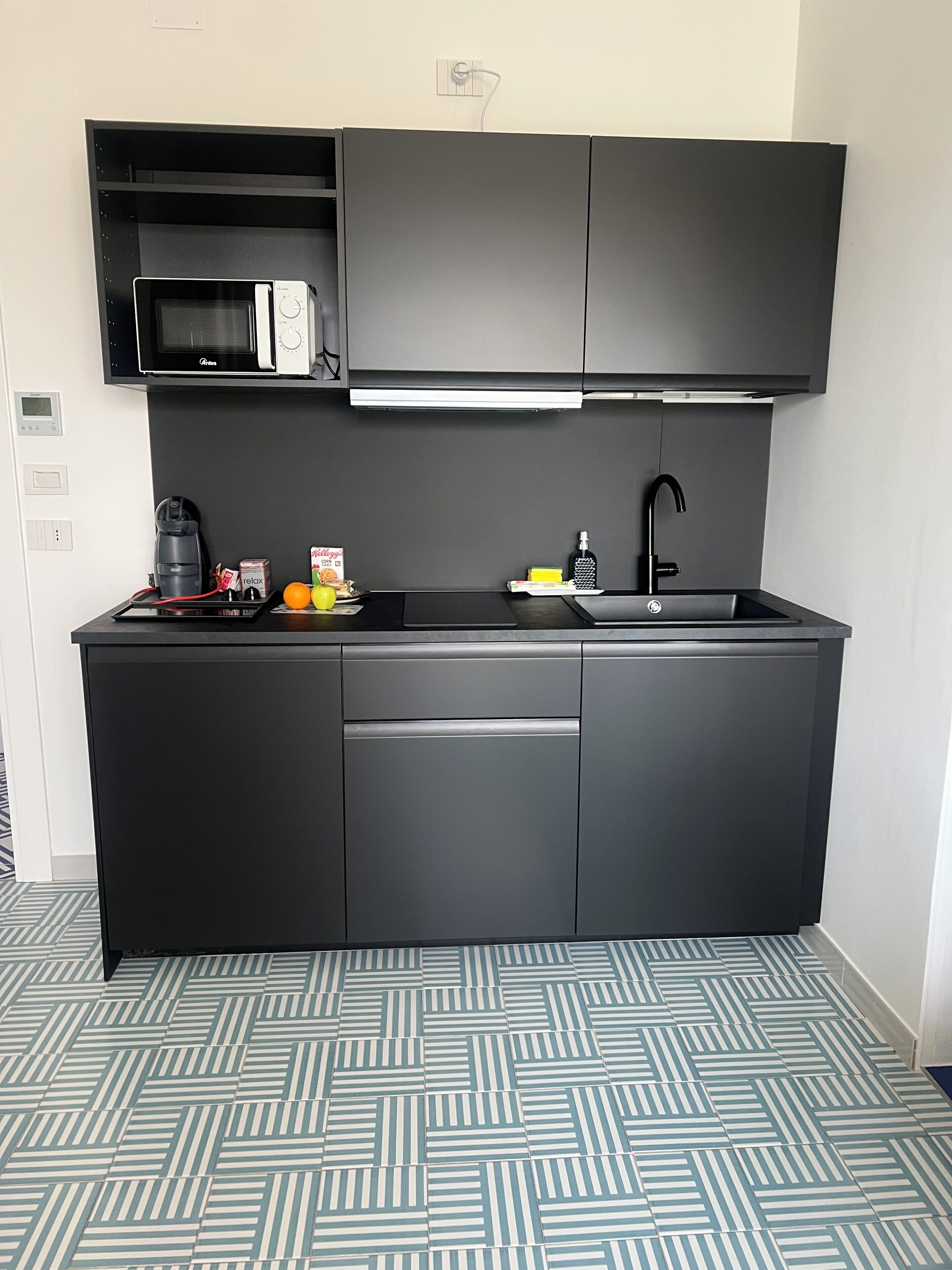 Una cocina compacta equipada con microondas, cafetera y lavamanos.
