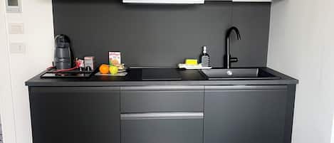 Una cocina compacta equipada con microondas, cafetera y lavamanos.