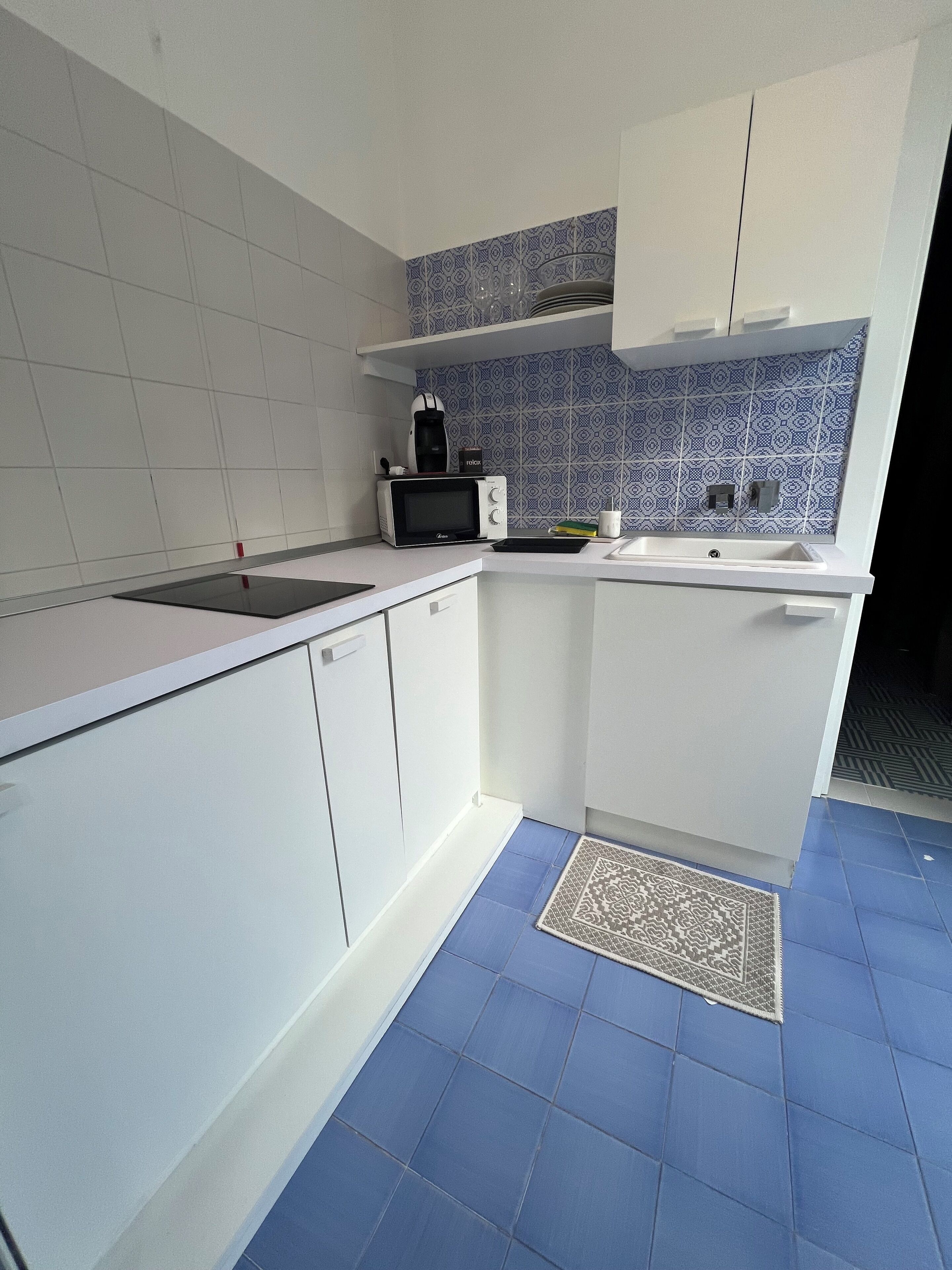 A kitchen with white cabinets, a microwave, and a coffee maker.