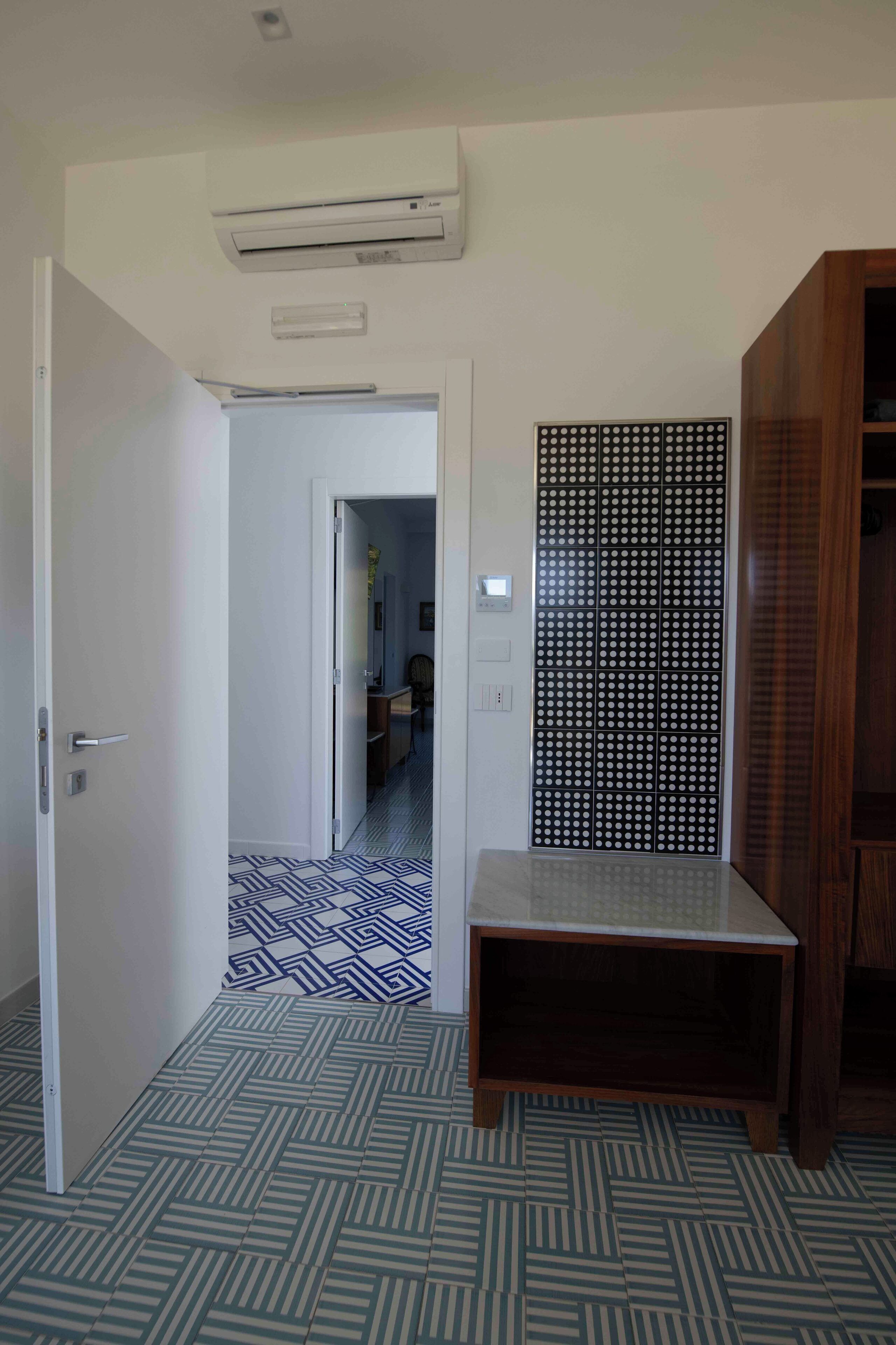 A room with a patterned floor, a wooden cabinet, and a white door.