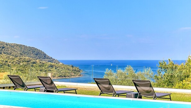 Un espace aménagé au bord de la piscine, avec des chaises longues et une vue sur la mer.