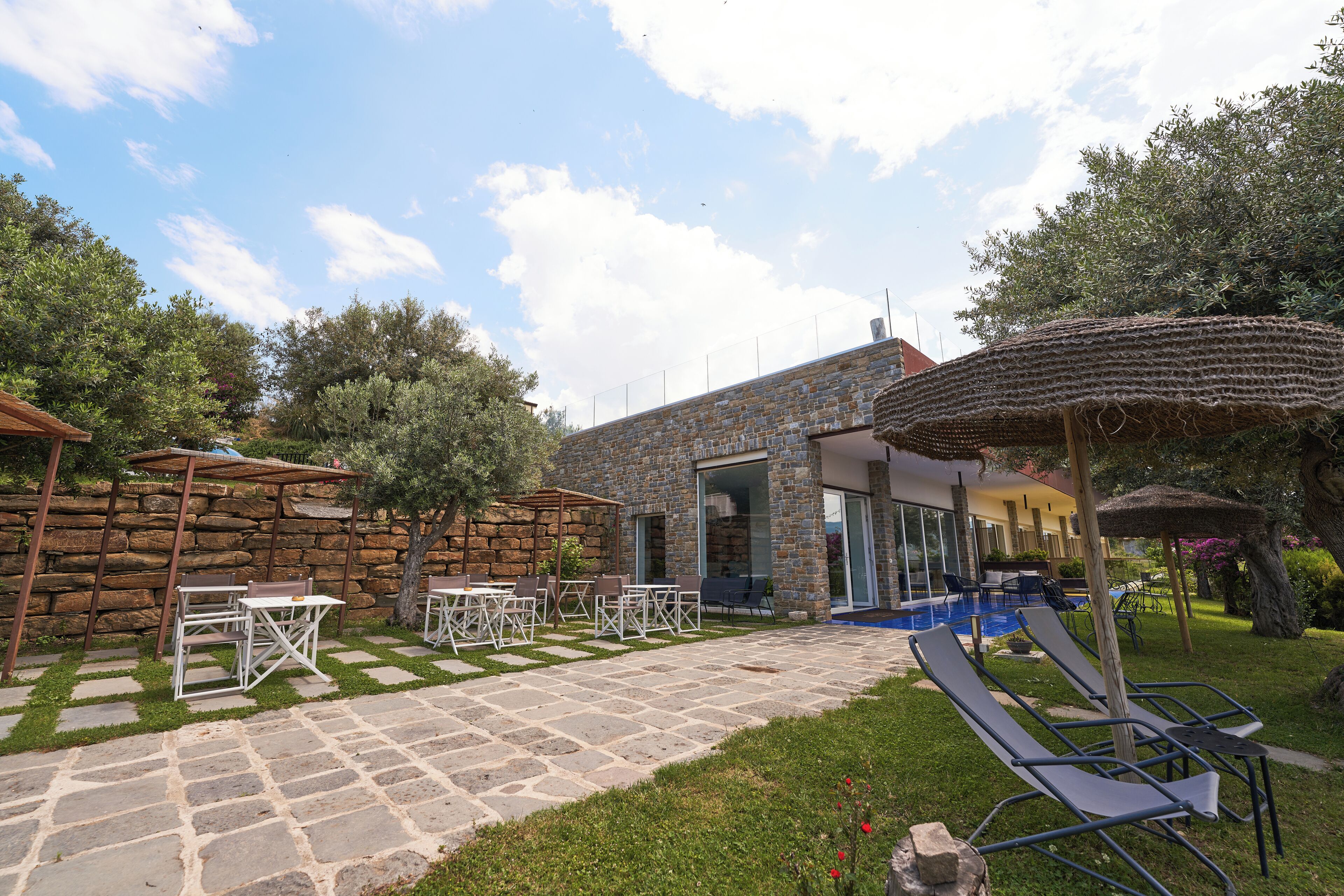 A stone building with a pool, outdoor seating, and a pergola.