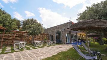 A stone building with a pool, outdoor seating, and a pergola.