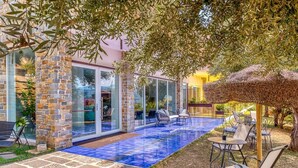 Une terrasse extérieure moderne avec une piscine aux carreaux bleus, des murs en pierre et des sièges d’extérieur.