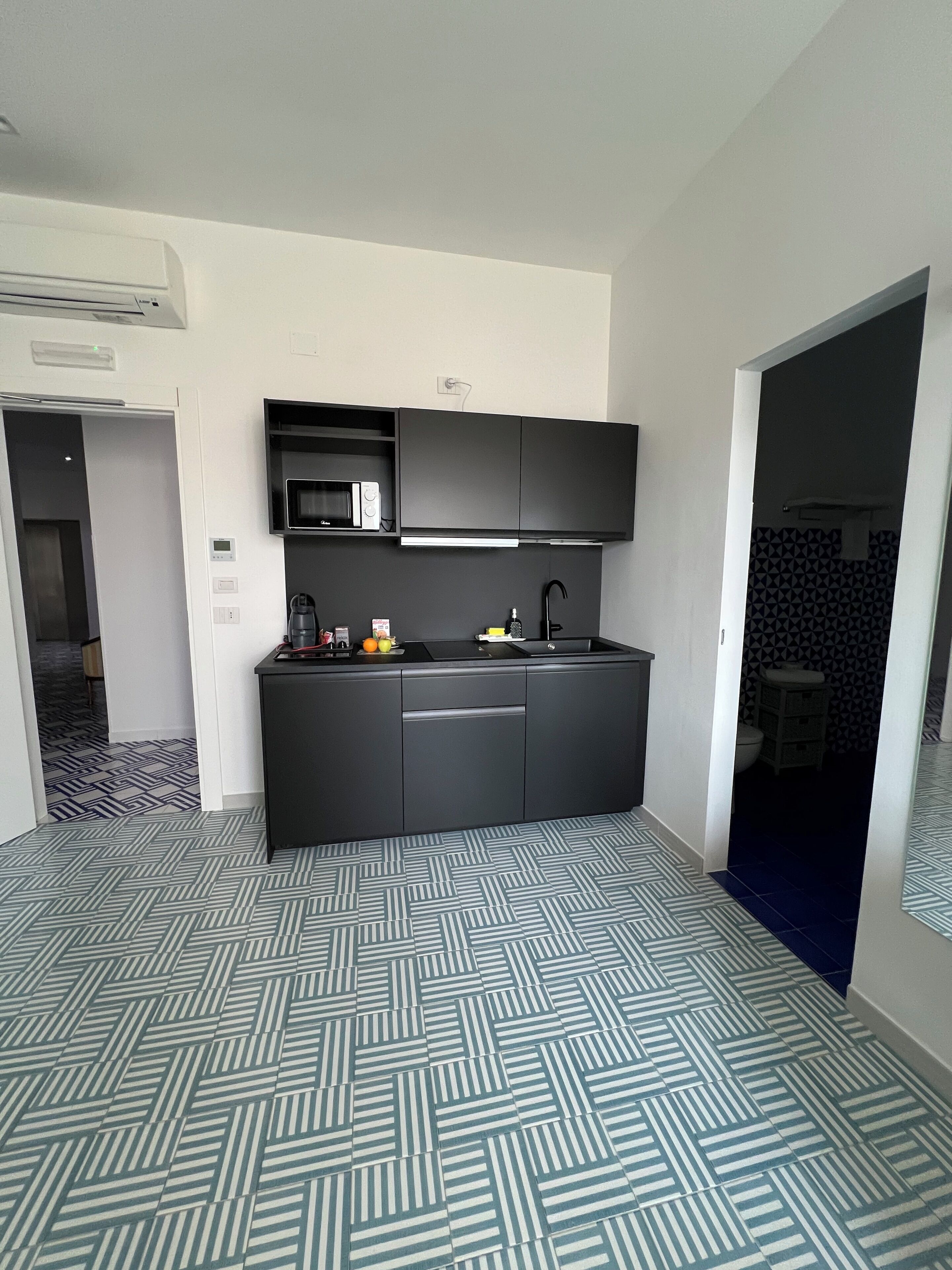 A modern kitchen with a microwave, coffee maker, and a small fruit bowl.