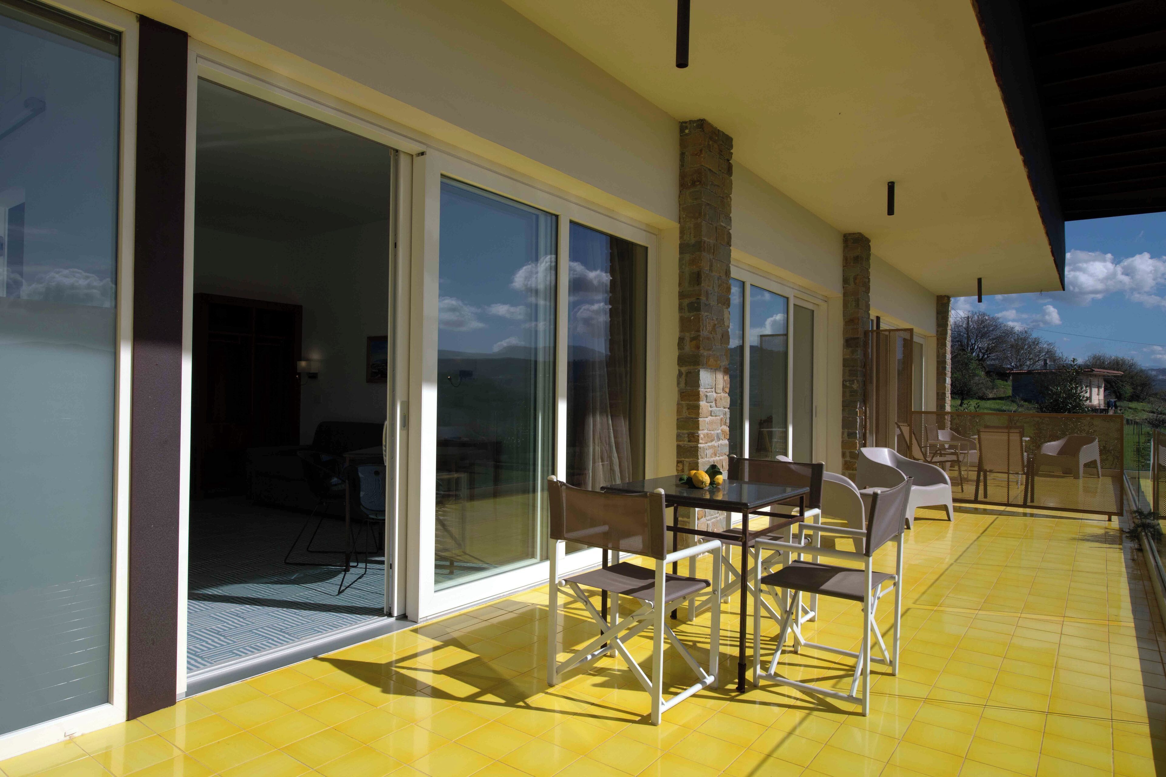 A patio with a table and chairs, a glass door leading to an interior space, and a stone pillar.