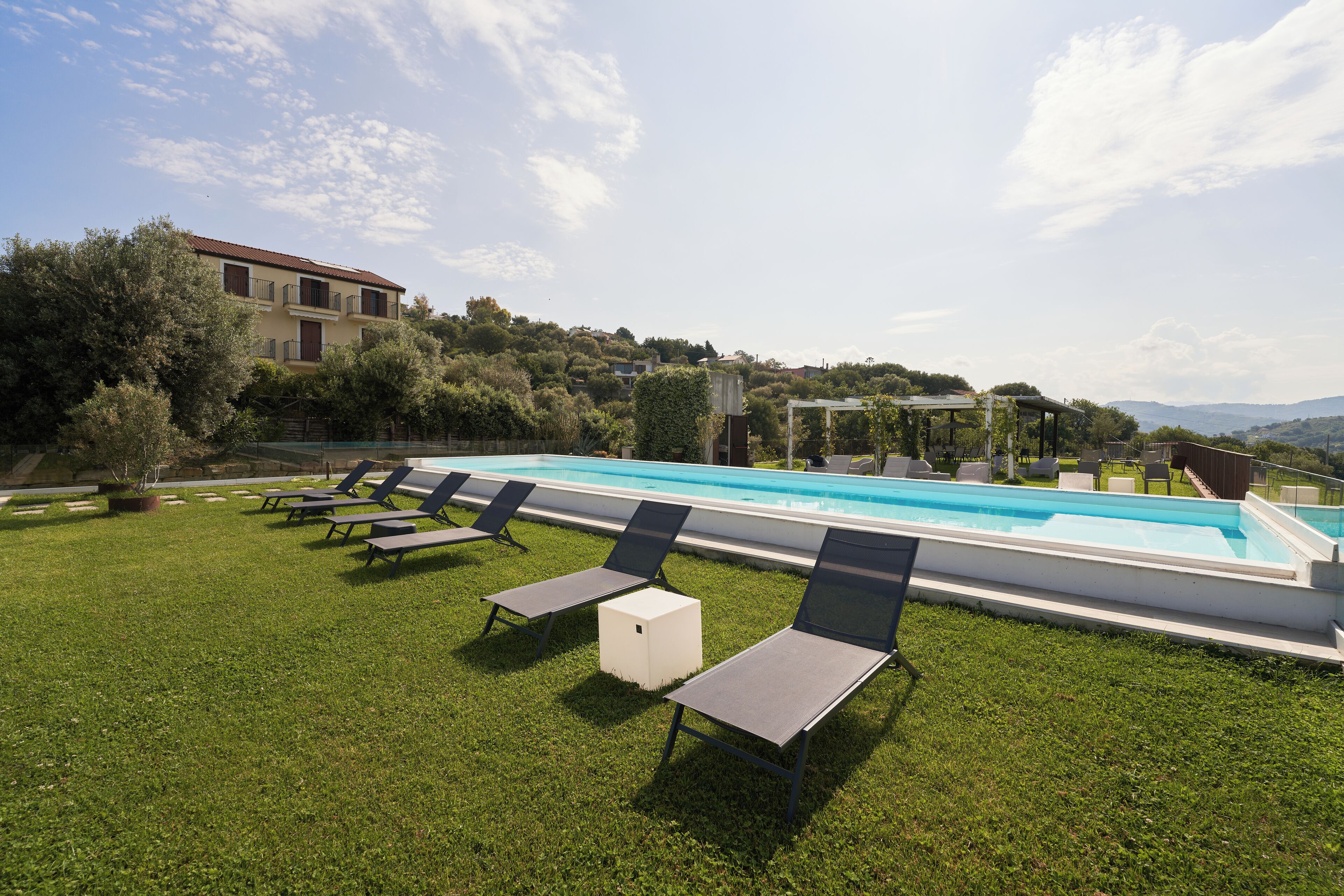 A swimming pool with lounge chairs and a grassy area.