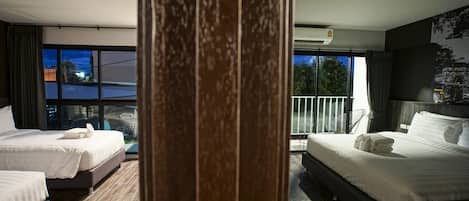 A hotel room with two beds, a large window, and a balcony.