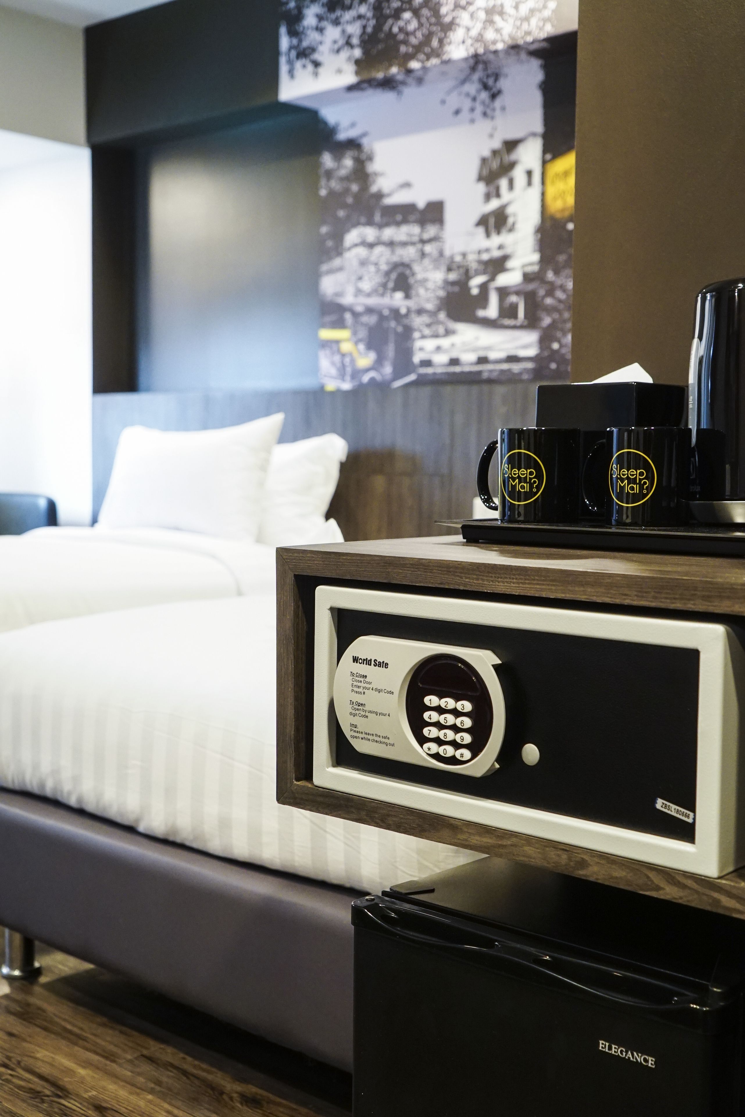 A hotel room with a bed, a coffee machine, and a safe.