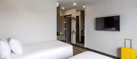 Habitación de hotel con dos camas, un televisor y una maleta amarilla.