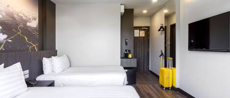 Une chambre d’hôtel avec deux lits, un téléviseur à écran plat, un porte-manteau et un radiateur fixé au mur.