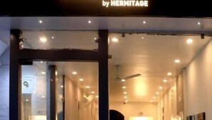 The entrance of Chakrah by Hermitage, featuring a modern design with glass doors, potted plants, and a well-lit interior. - Chakrah by Hermitage (Narendranagar)